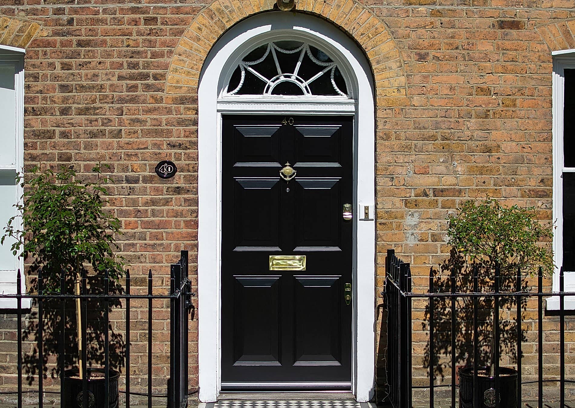 Georgian front door and fanlight door frame. Door painted black, frame painted white. Polished brass door funiture