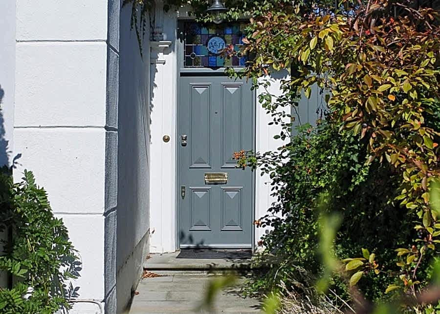 four panelled door fitted into a late Georgian London house. Door and frame painted a light green/ grey colour. Stained glass fitted above the door.
