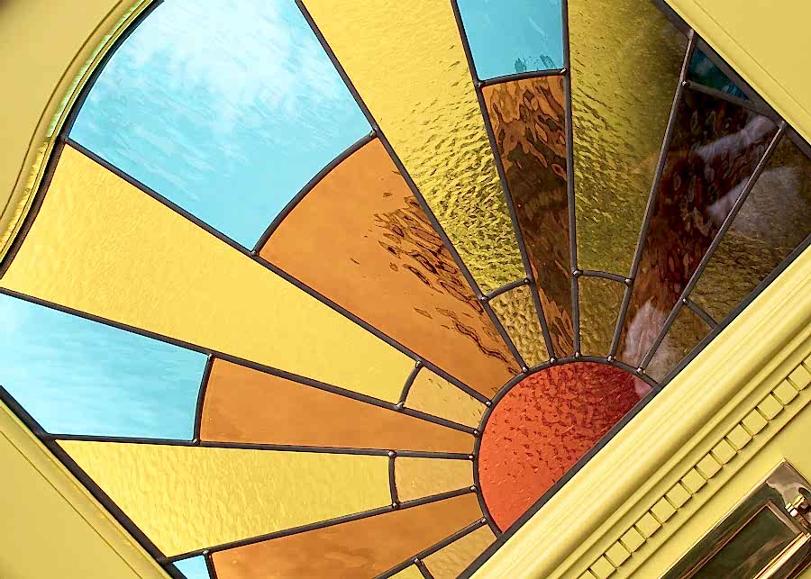 1930s front door with stained glass. Door is painted bright yellow and has decorative 1930s leaded glass